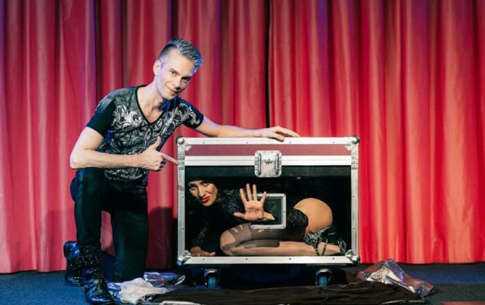 Zauberkünstler vor einem rotem Vorhang in Lörrach bei einer Zaubershow mit Assistentin