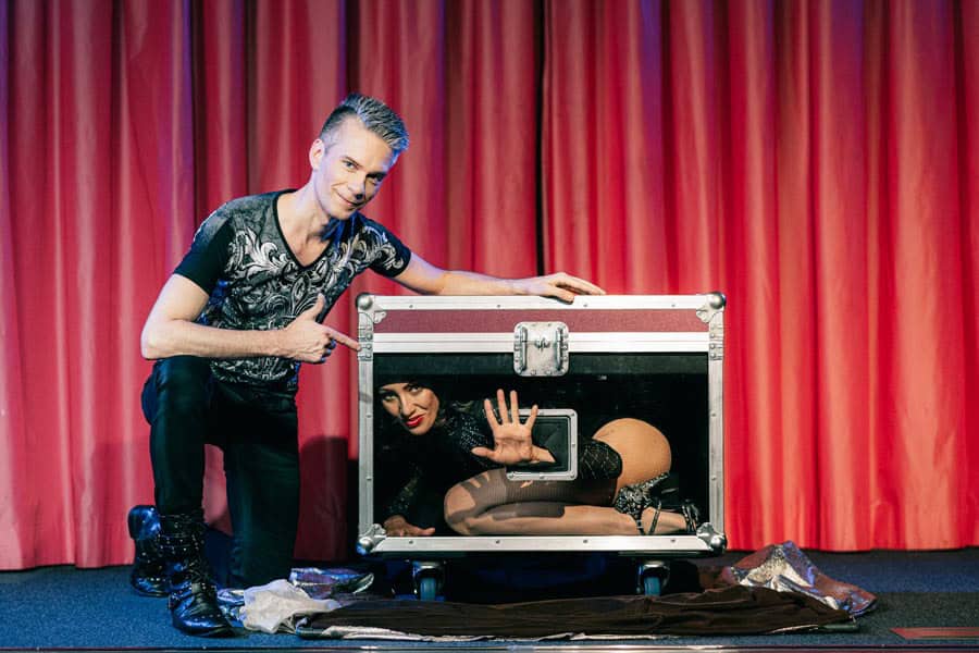 Zauberer Lörrach buchen Zauberkünstler vor einem rotem Vorhang in Lörrach bei einer Zaubershow mit Assistentin